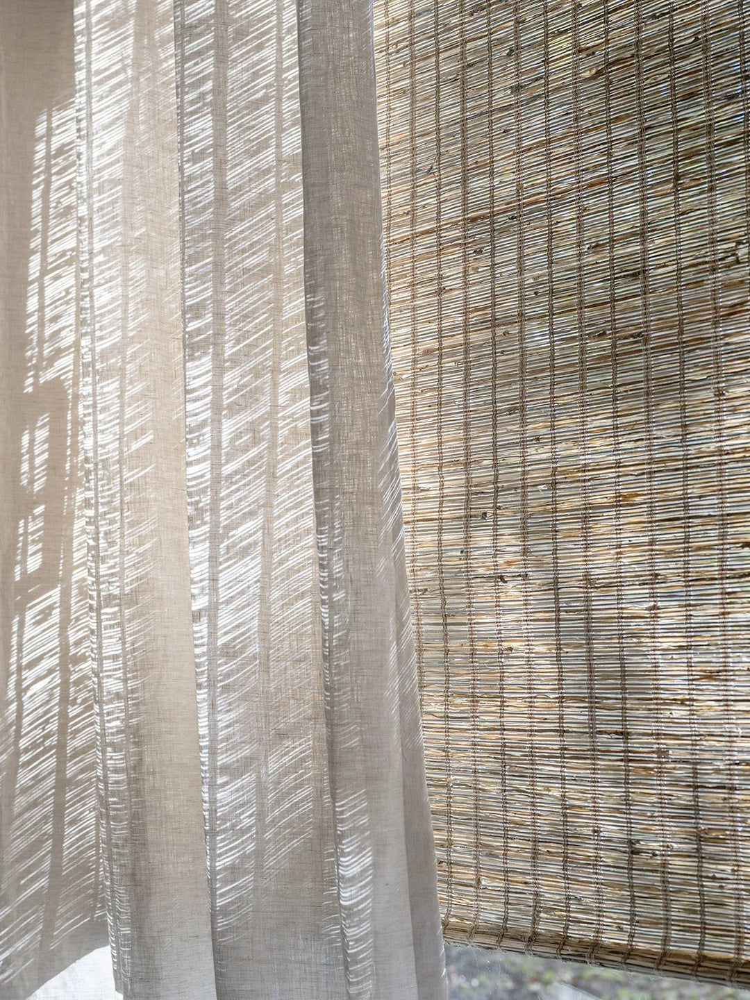 Woven Roman Shades in natural tan jute with a textured horizontal weave and warm cinnamon-toned variation