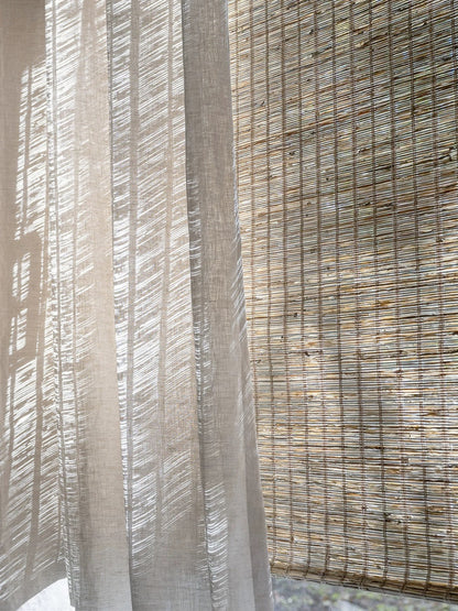 Woven Roman Shades in natural tan jute with a textured horizontal weave and warm cinnamon-toned variation